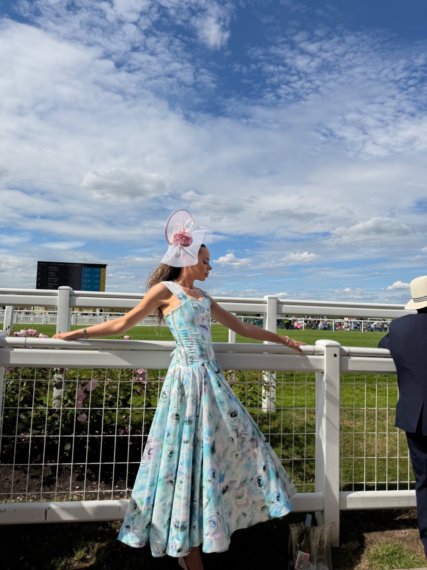 A member posing by the rail in a pastel floral gown