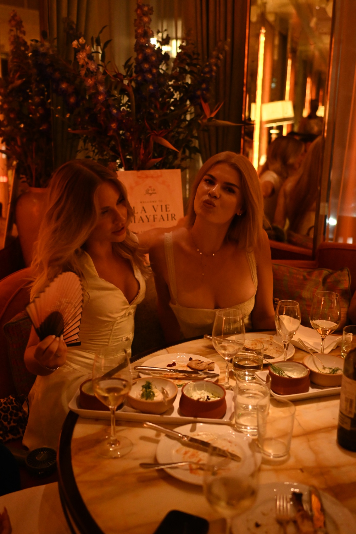 Two members posing together in front of the La Vie Mayfair welcome sign
