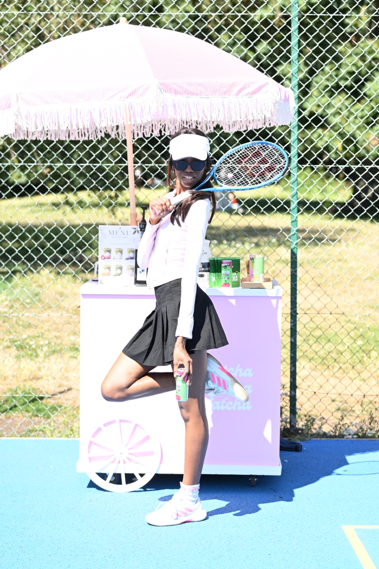 A member in a visor swinging her racket by the matcha cart