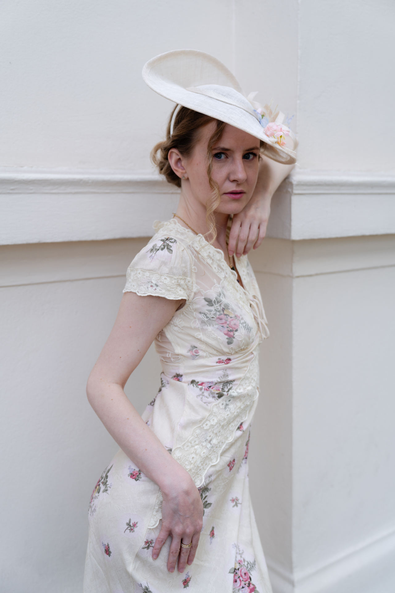 A member in a vintage floral dress and cream hat