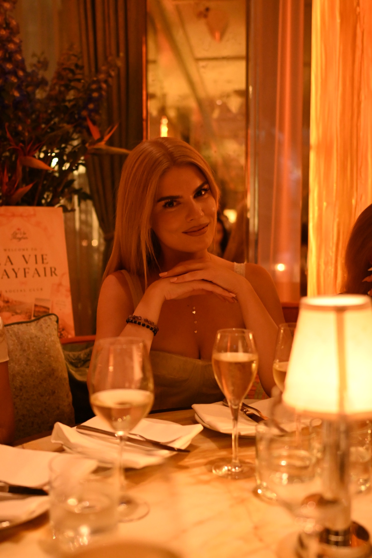 A member smiling at the candlelit table beside the welcome sign