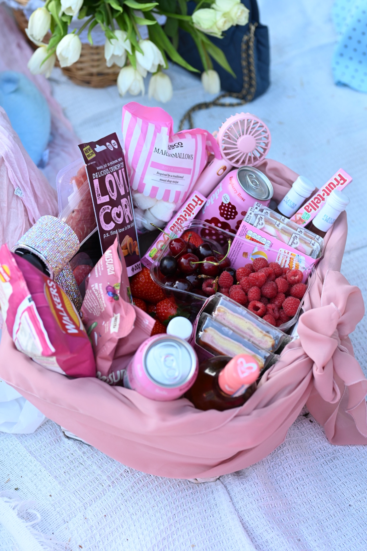 A pink-themed picnic hamper filled with treats and flowers