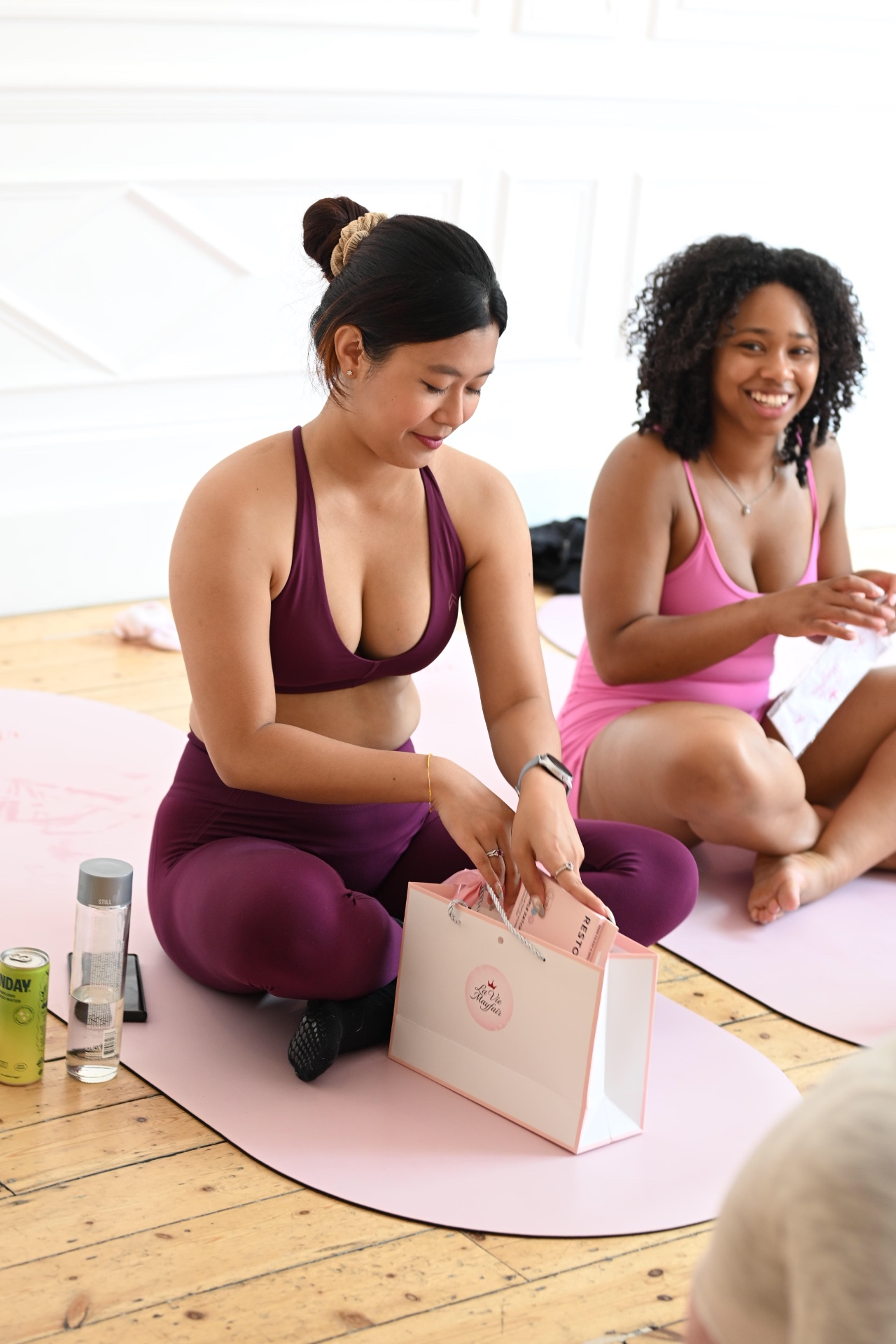 Two members opening their La Vie Mayfair gift bags after class