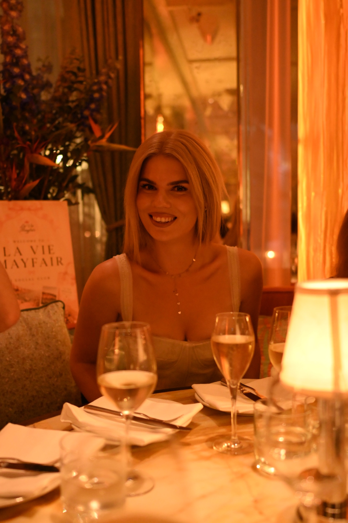 A member smiling at the table beside the La Vie Mayfair welcome sign