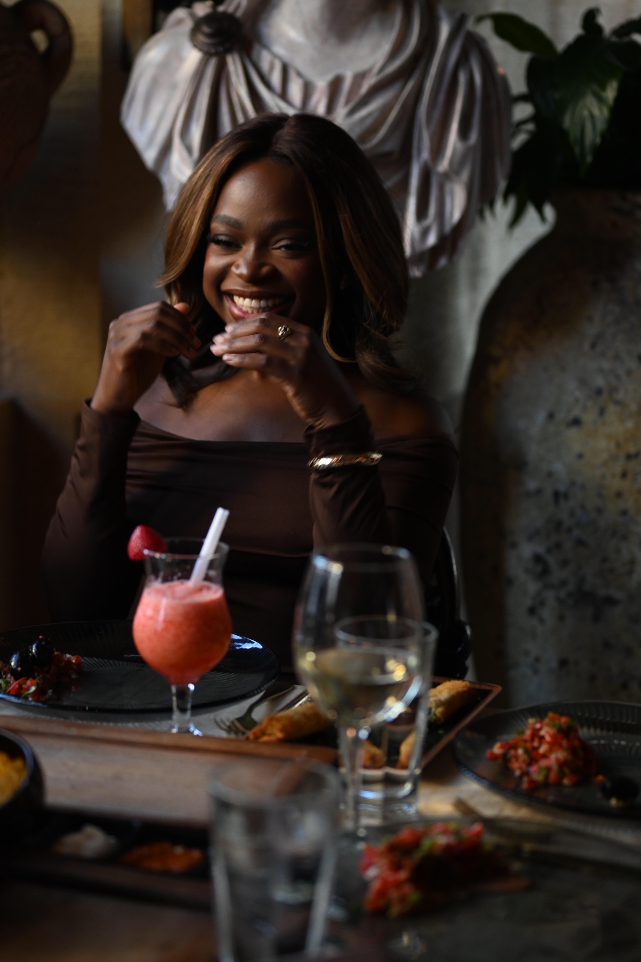 A member laughing with a strawberry daiquiri at the table