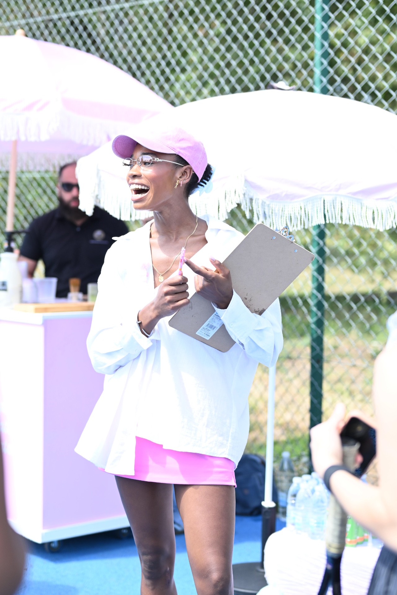 A member hosting the tennis social with a clipboard under pink parasols