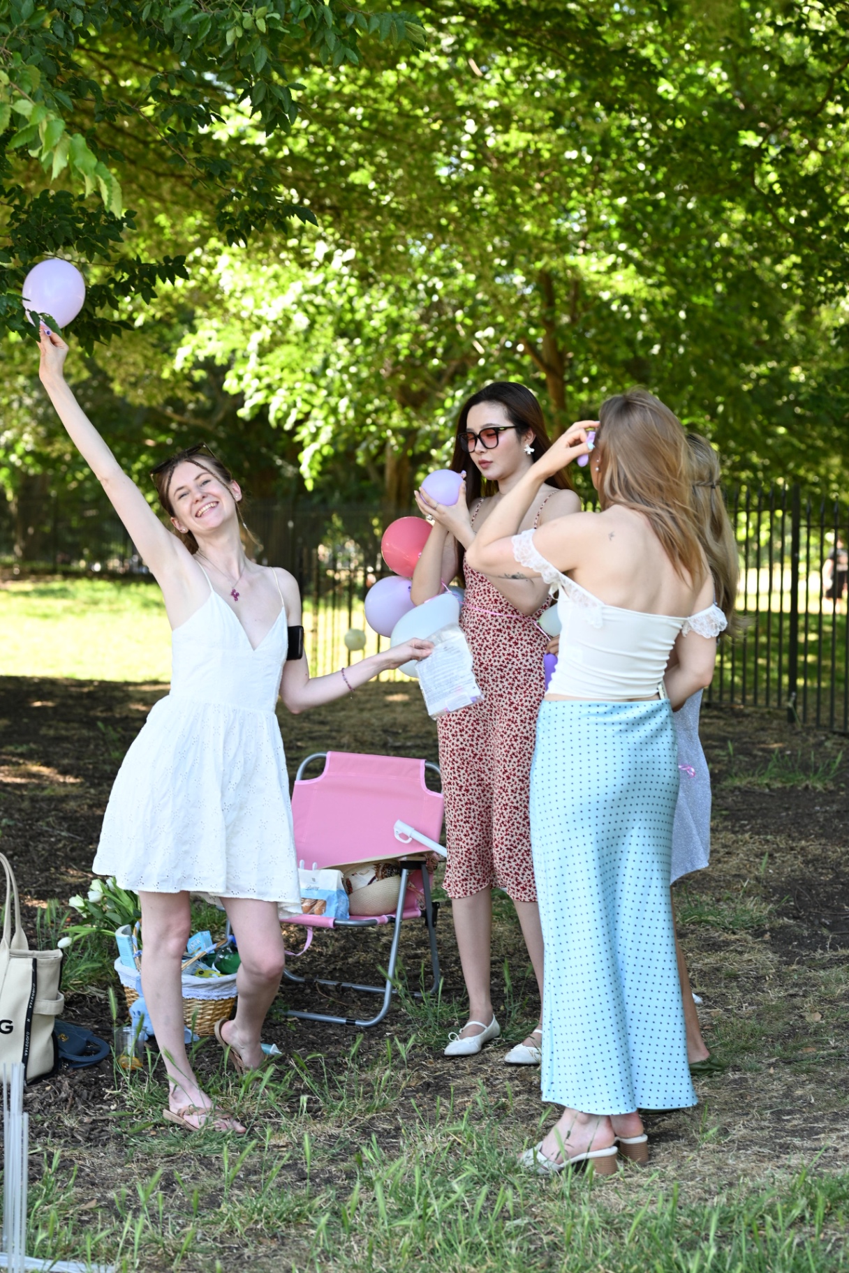 Members blowing up pastel balloons under the trees
