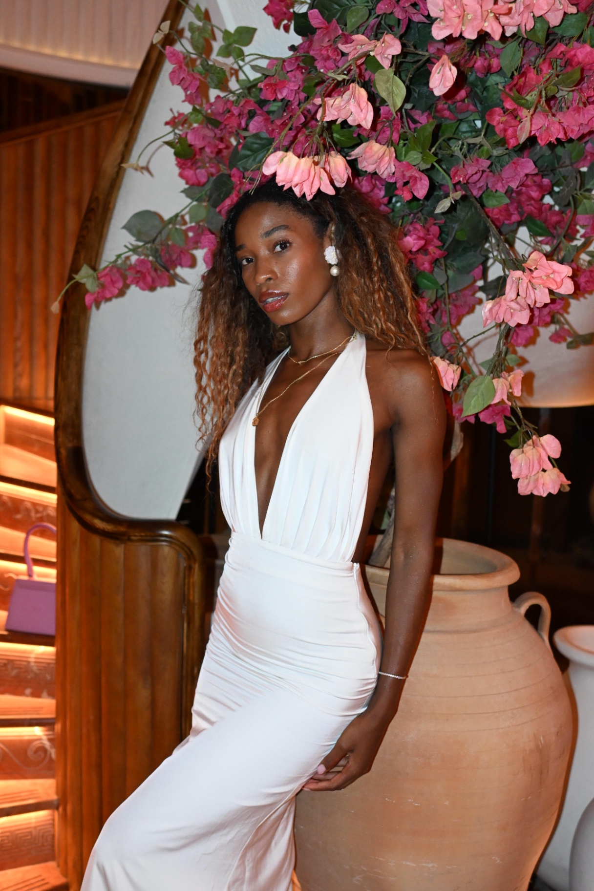 A member in a white gown beside pink bougainvillea at Gaia Mayfair