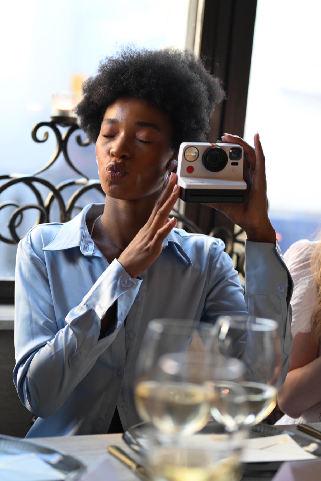A member blowing a kiss with a Polaroid camera