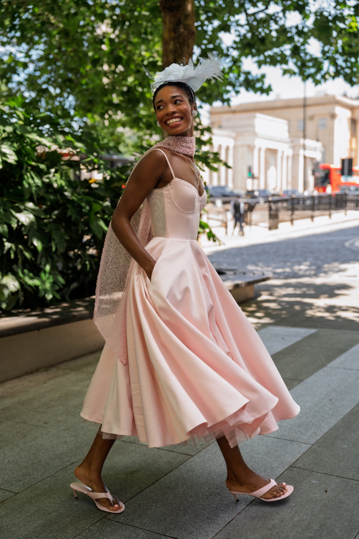A member twirling in a blush pink gown and feathered hat